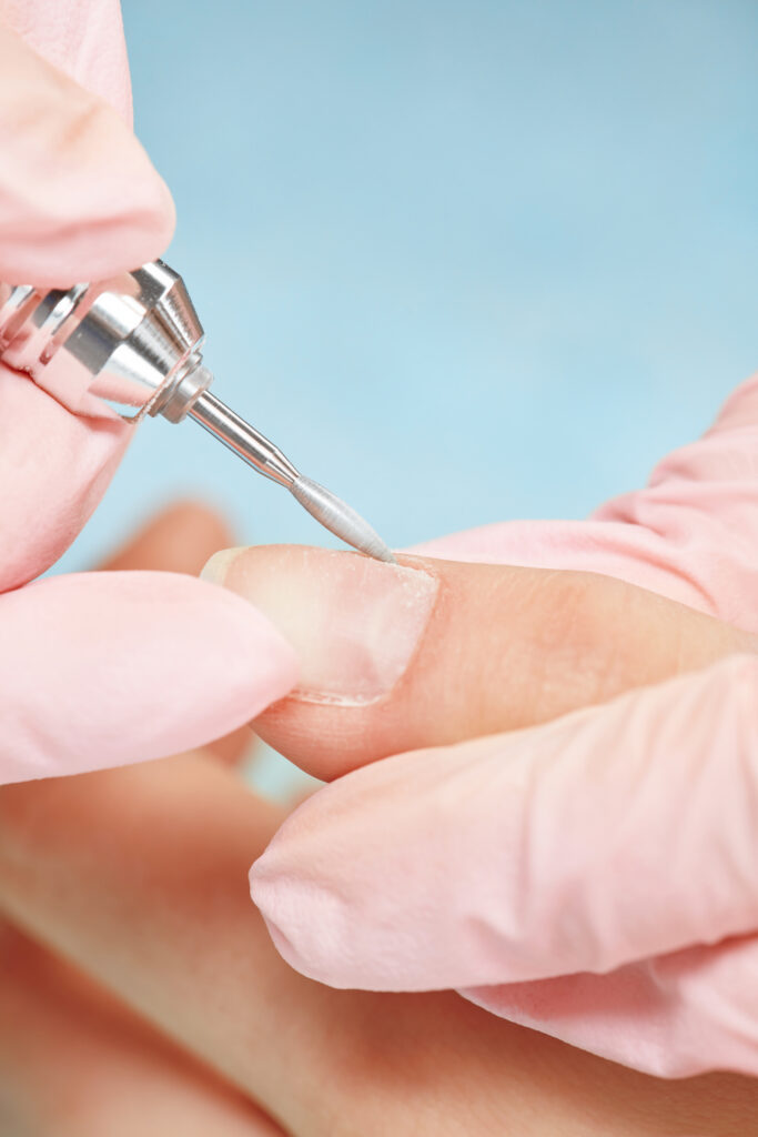 manicure process in beauty salon, cleaning of nails by a milling cutter.
